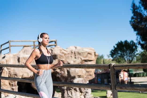 Beautiful young sports Woman running jogging in a park outdoors listening music