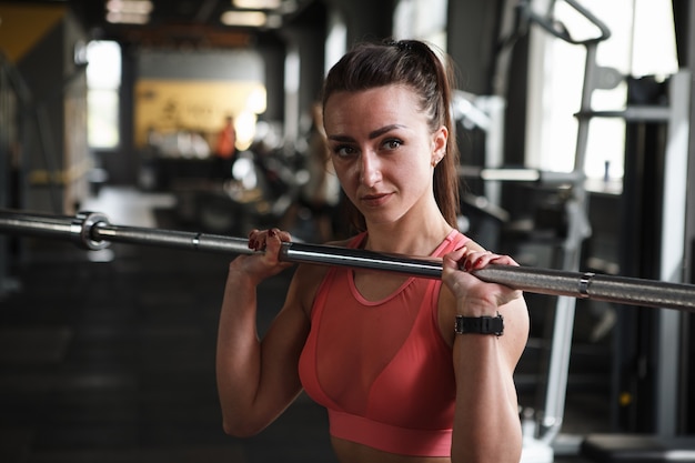 Beautiful young sportswoman doing push press exercise with barbell