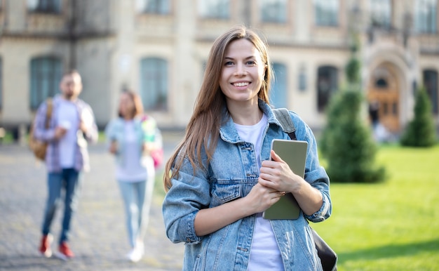 Beautiful young student girl with a backpack and books by the university