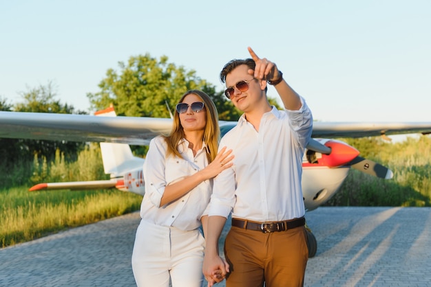 Beautiful young stylish couple in official clothes standing in private plane