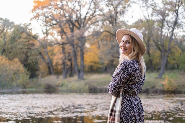 Beautiful young stylish woman in hat walks in nature in autumn park in fall.