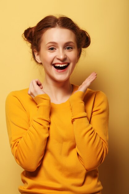 Beautiful young surprised redhair woman over yellow background