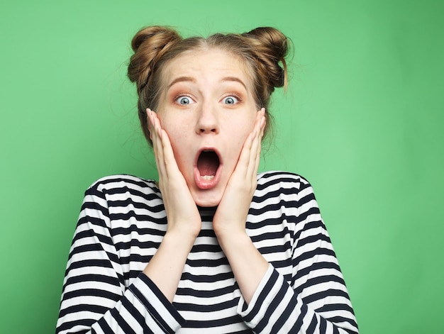 Beautiful young surprised woman over green background