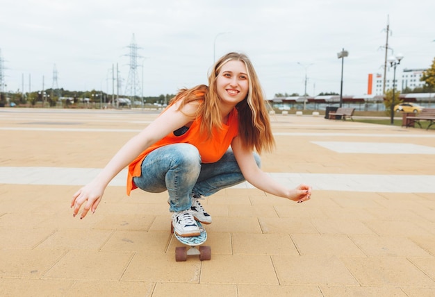 A beautiful young teenage girl rides a skateboard in sunny weather generation z