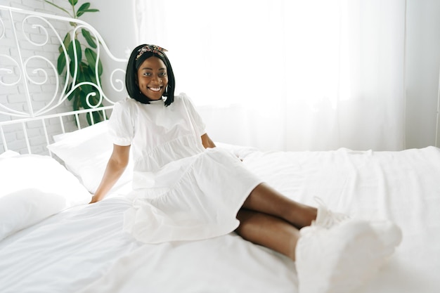 Beautiful young thoughtful african woman sitting in morning bed