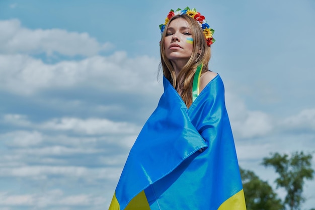 Beautiful young ukrainian woman covering with national flag with sky in the background