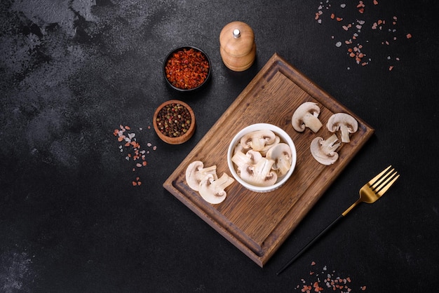 Beautiful young white champignons torn to slices on a dark concrete background