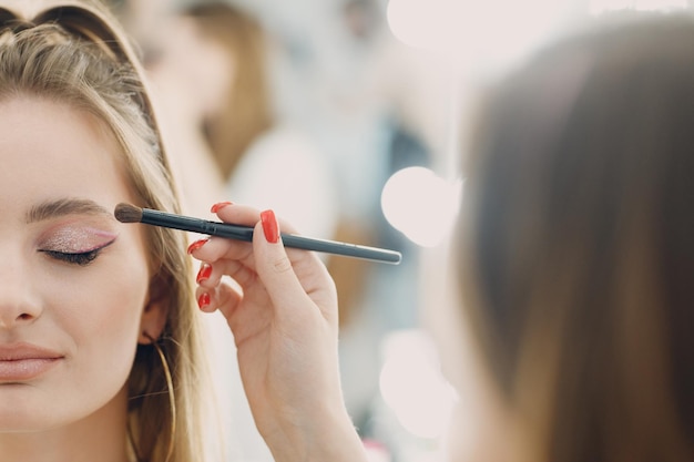 Beautiful young woman applying makeup beauty visage brush