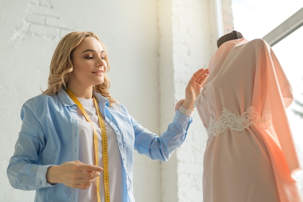 beautiful young woman in the atelier at work makes a dress on a mannequin