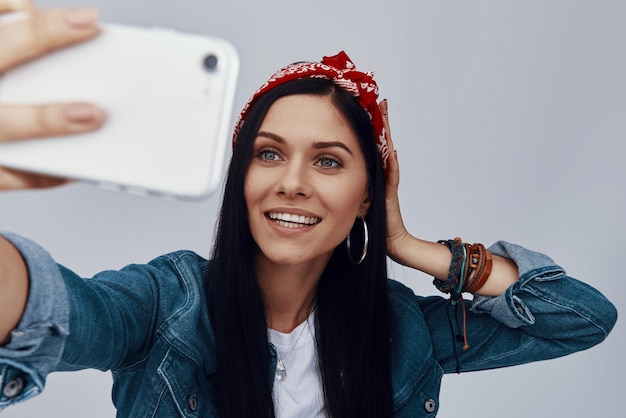 Photo beautiful young woman in bandana making selfie and smiling