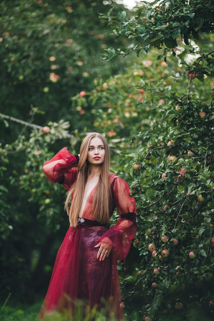 A beautiful young woman in a bard dress is gazing on in the field and the garden.