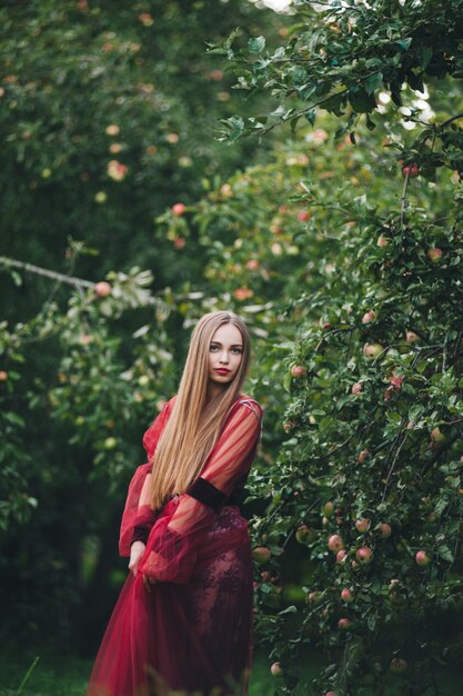 A beautiful young woman in a bard dress is gazing on in the field and the garden.