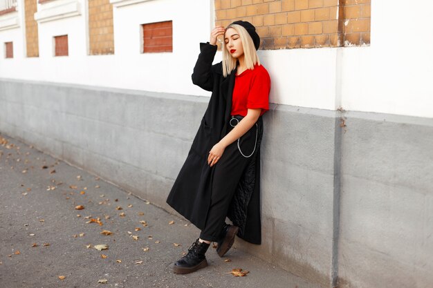 Beautiful young woman in black autumn fashion clothes posing outdoors near building