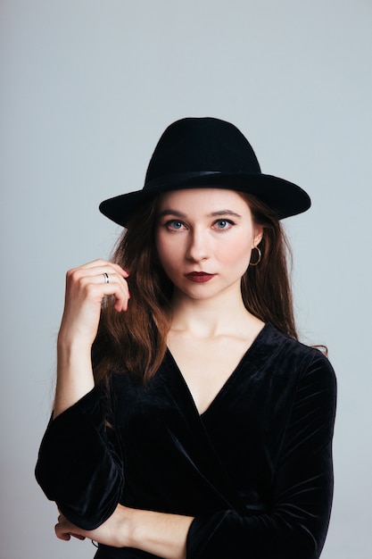 Beautiful young woman in black dress and hat on white background. Girl in black isolated