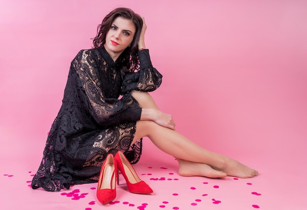 Beautiful young woman in black dress sitting with trendy shoes. Fashion photo