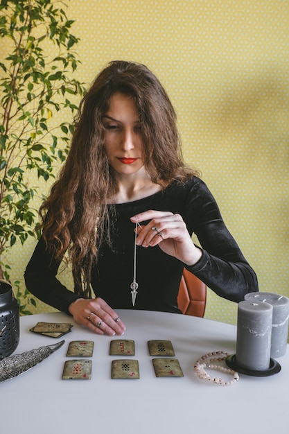 Photo beautiful young woman in a black velvet dress holds a crystal on a silver chain