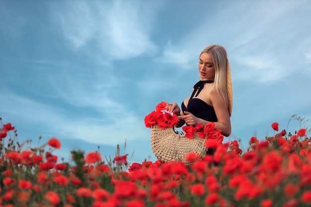 Beautiful young woman blonde walks on a flowering field of poppies at sunset