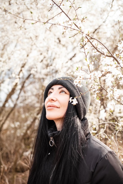 Beautiful young woman in blooming cherry blossoms garden