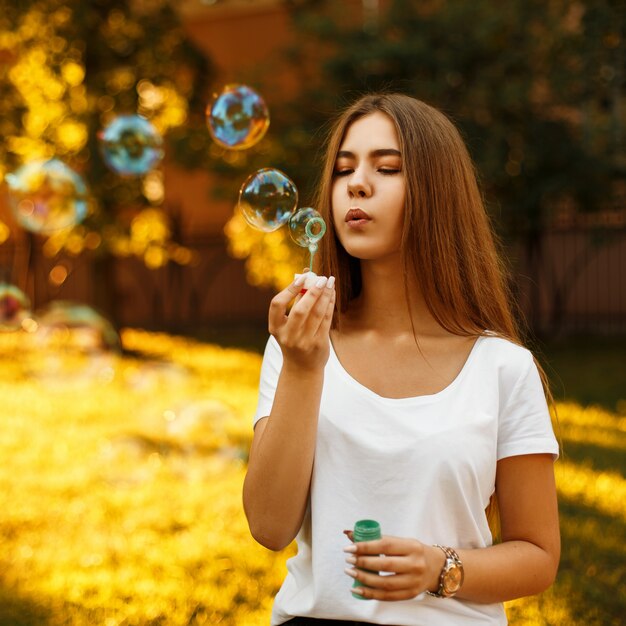 Beautiful young woman blowing soap bubbles