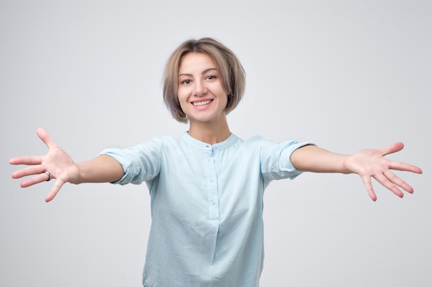 Beautiful young woman in blue shirt offering a hug