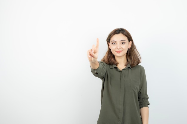 Beautiful young woman in casual outfit standing over white wall. High quality photo