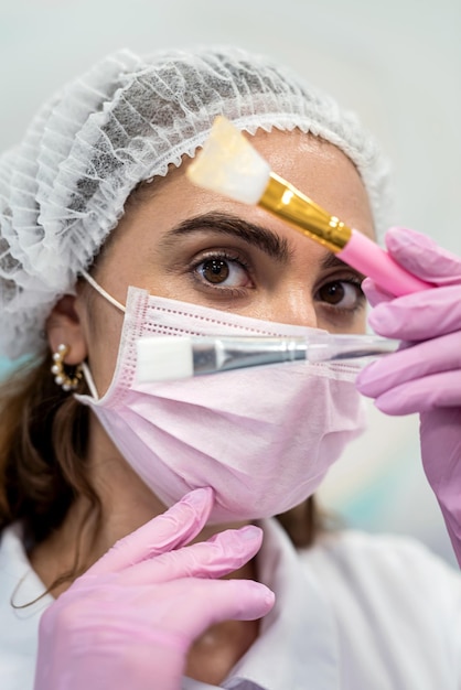 Beautiful young woman cosmetologist in a cap on her head near a mirror with bones for applying different masks beauty salon concept beauty procedures