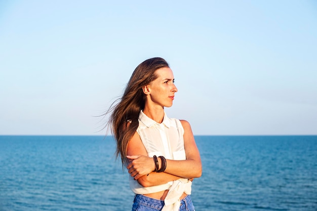 Beautiful young woman in denim shorts and shirt at the sea