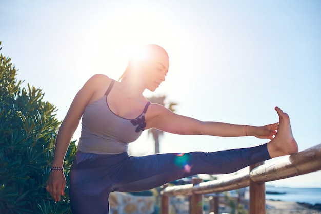 Photo beautiful young woman doing stretching exercises by the sea.