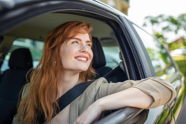 Beautiful young woman driving her new car at sunset Woman in car Close up portrait of pleasant looking female with glad positive expression woman in casual wear driving a car