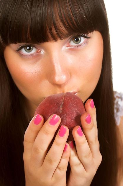 Beautiful young woman eating a peach