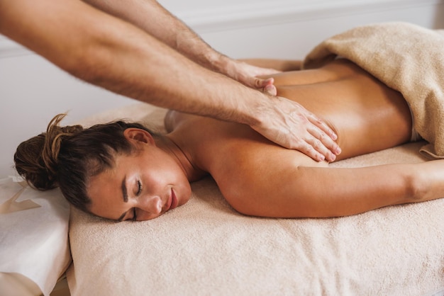 Beautiful young woman enjoying back massage from a professional at the beauty salon.