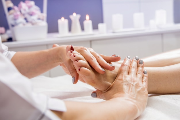 Beautiful young woman enjoying foot massage in spa salon.