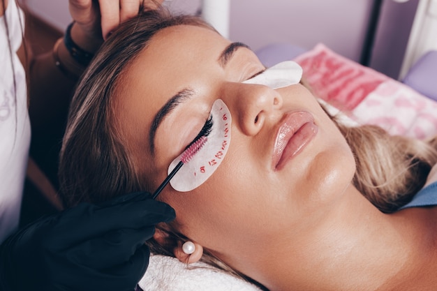 Beautiful young woman at eyelash extension procedure. Cosmetics and body care concept.