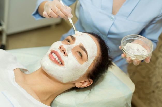 beautiful young woman on a facial treatment in a beauty salon applying a cream