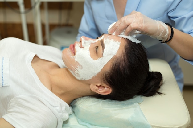 beautiful young woman on a facial treatment in a beauty salon applying a cream