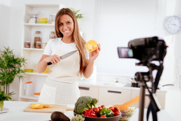 Beautiful young woman filming her blog broadcast about healthy food at the home.