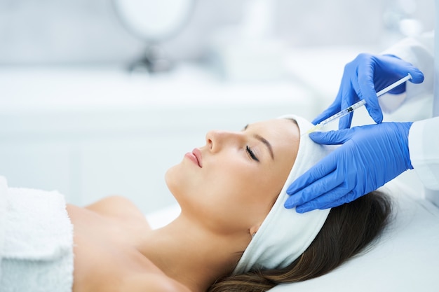 Beautiful young woman getting a acid face treatment at beauty salon.