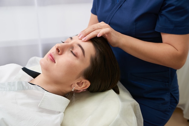 Beautiful Young Woman Getting a Face and head Treatment at Beauty Salon