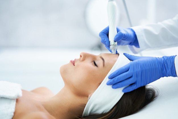 Beautiful young woman getting a face treatment at beauty salon.