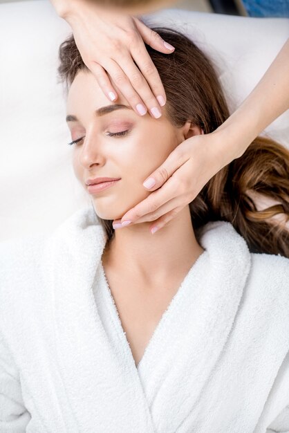 Photo beautiful young woman getting facial massage lying on the couch. top view focused on the face