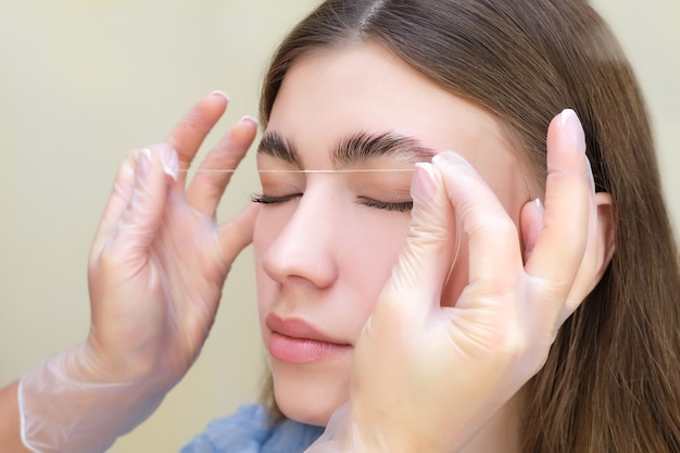 Beautiful young woman got correction of eyebrows in a beauty salon