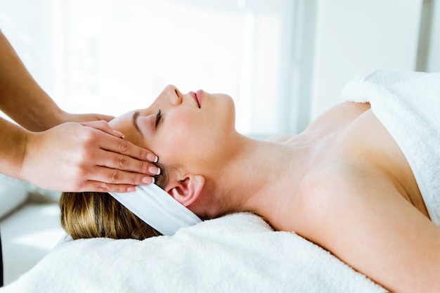 Beautiful young woman having spa facial massage in beauty salon.