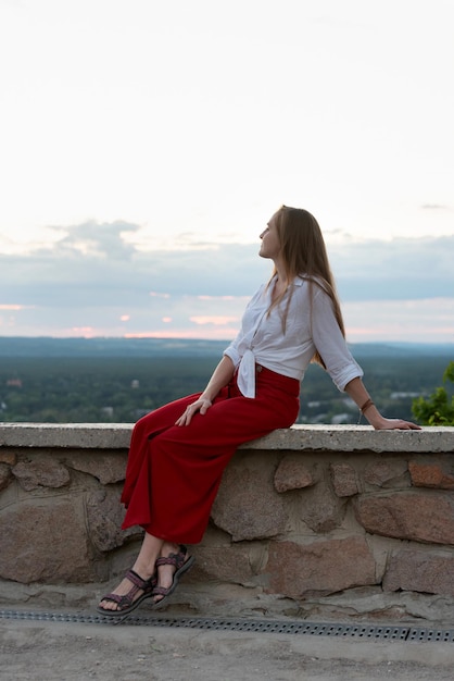 Beautiful young woman on hill is resting with view of nature Vertical frame