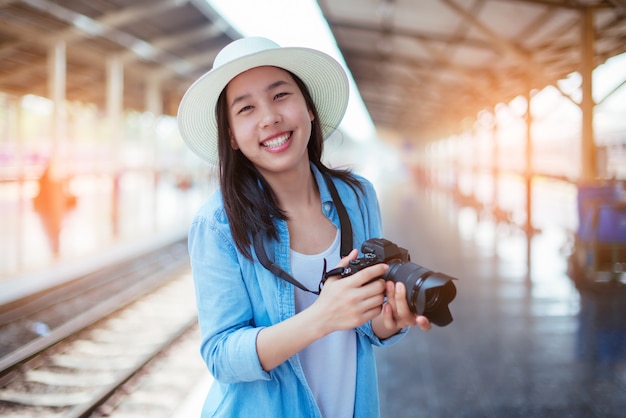 Beautiful young woman holding a camera in her hand with a smile while traveling by train.