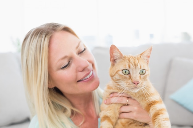 Beautiful young woman holding cat at home