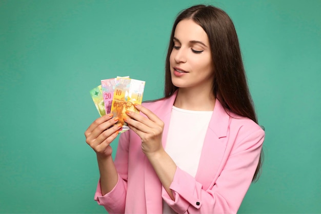 Beautiful young woman holding and looking at swedish krona banknotes looking positive