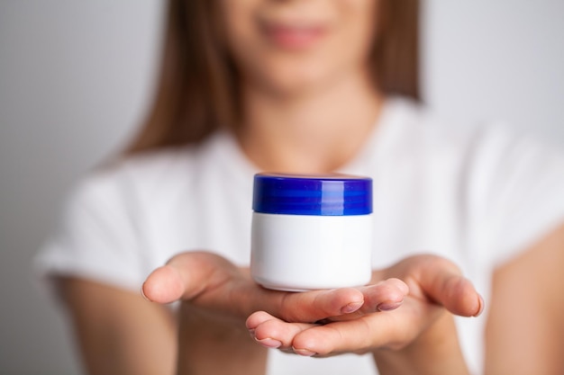 Beautiful young woman holding moisturizer cream on her hands