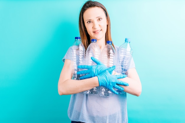 Beautiful young woman holding plastic bottles on blue background. recycling concept. environmental care