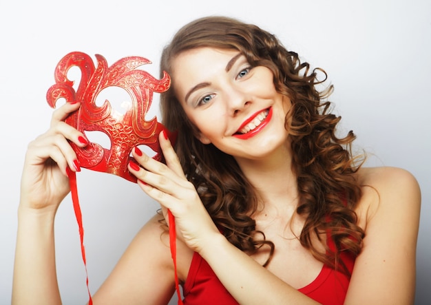 Beautiful young woman holding red mask