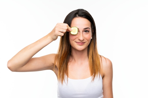 Beautiful young woman holding slices of cucumber over isolated white wall